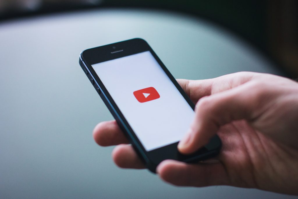 seo para youtube - mão com smartphone, na tela o logo do youtube