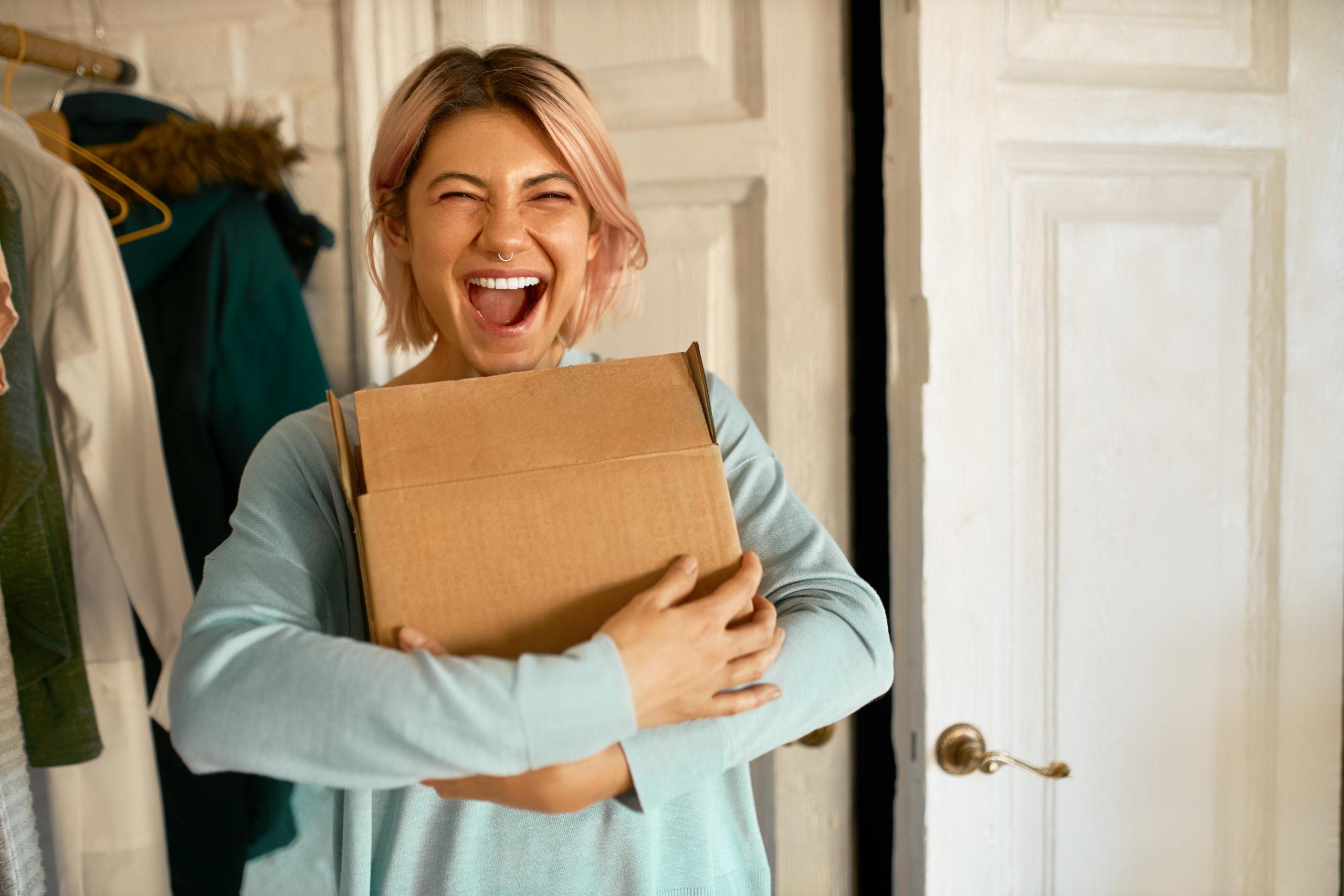 mulher feliz abraçando uma caixa de papelão - encantar clientes